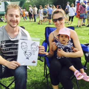 Family at festival holds up custom artwork by caricature artist Corrina
