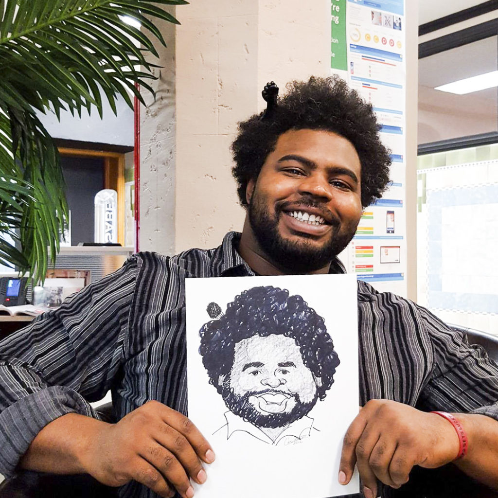 Black man with comb in hair proudly presenting his custom caricature art
