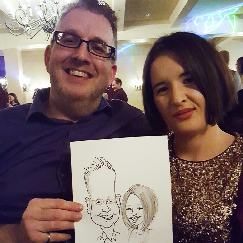 Couple holding caricature of themselves at banquet hall Saskatoon