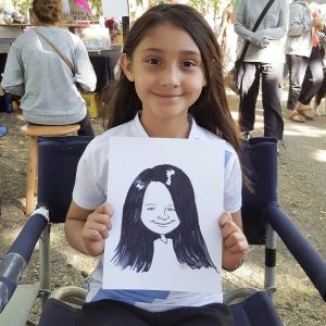 Young girl displays her caricature at outdoor event